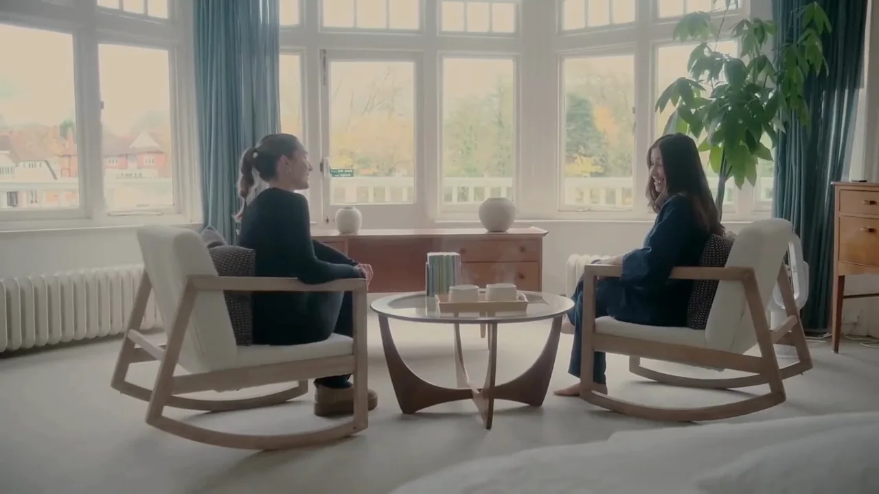 Two guests in rocking chairs in the riverside lounge, bay windows onto the river