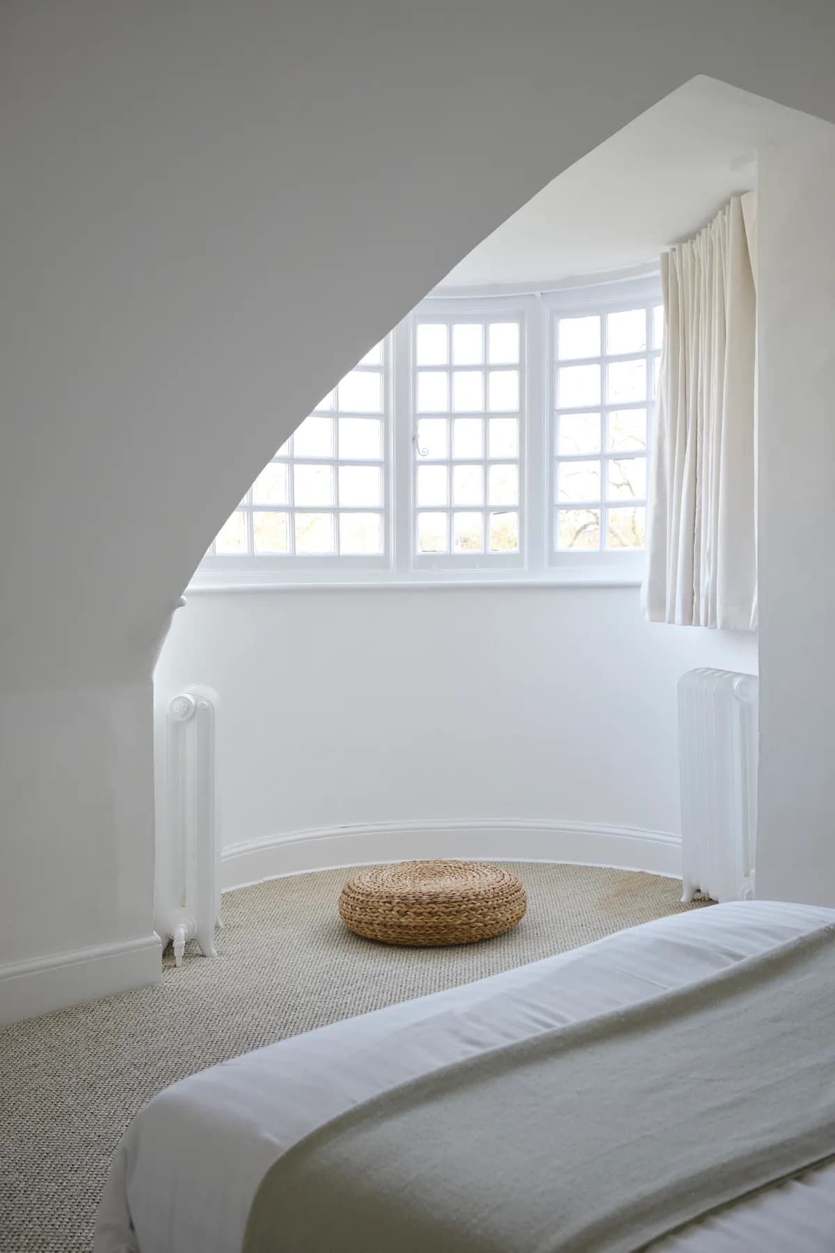 A curved bay window beneath the eaves of a Tiny Room
