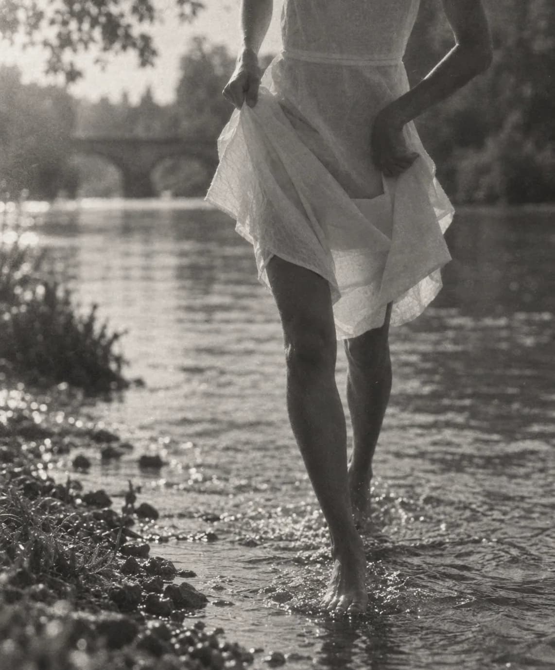 Black-and-white image of a woman walking barefoot at the river’s edge